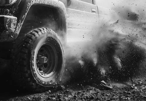 Off-road vehicle with rugged tires driving through mud and dirt.